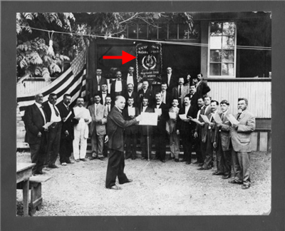 photograph of a group of men surrounding a banner in the German language