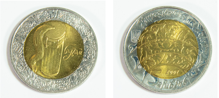 Front of coin portraying buhay drum on gold background with a silver decorative border, back of coin showcasing arching decorative pattern and coin denomination