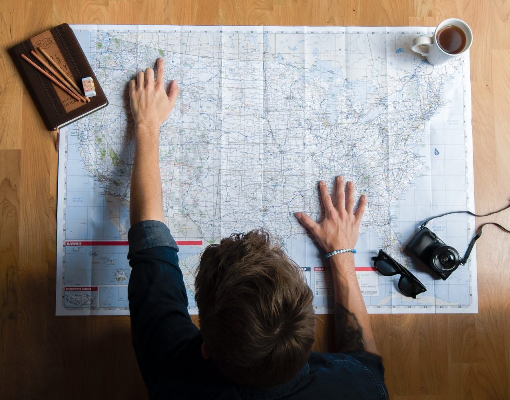 Unrecognizable man examining map while planning travel at home