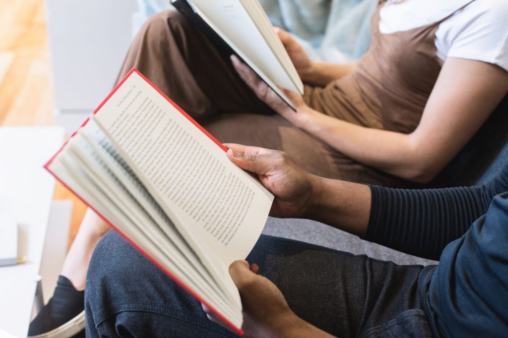 A man reading a book beside a woman reading a book 