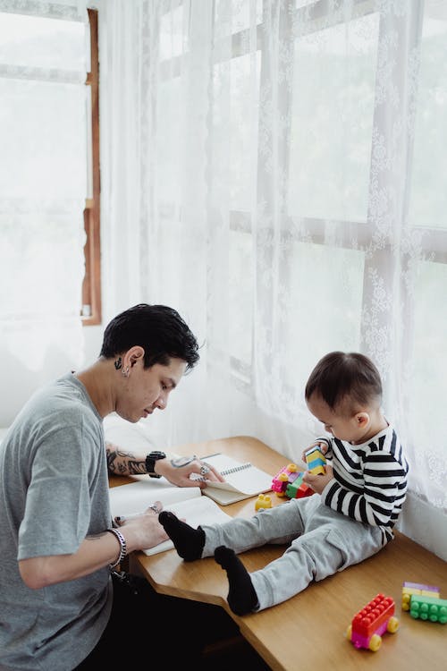 Father is studying while kid is playing.