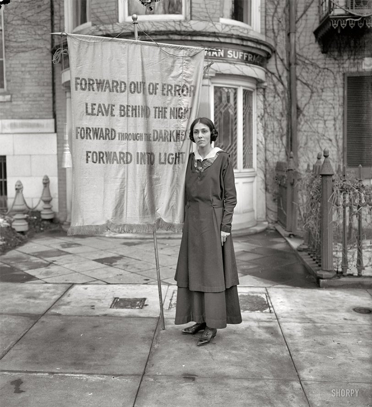 Woman holding banner at Inez Milholland memorial.